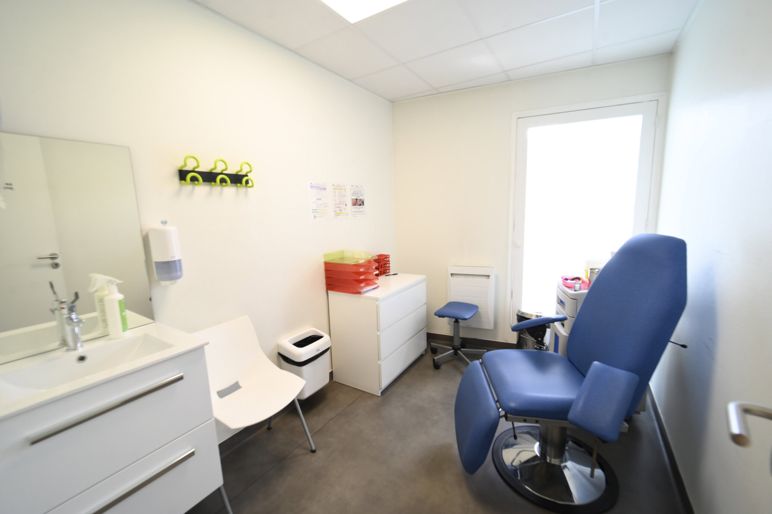 Intérieur d'une salle de consultation médicale comprenant un fauteuil d'examen, un lavabo, des armoires et du matériel médical du Laboratoire Givet Bio Ard'Aisne.