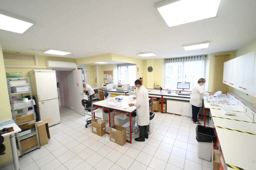 Trois techniciens de laboratoire en blouse blanche travaillant dans le Laboratoire Sedan La Marck, lumineux et moderne, doté de divers équipements médicaux.