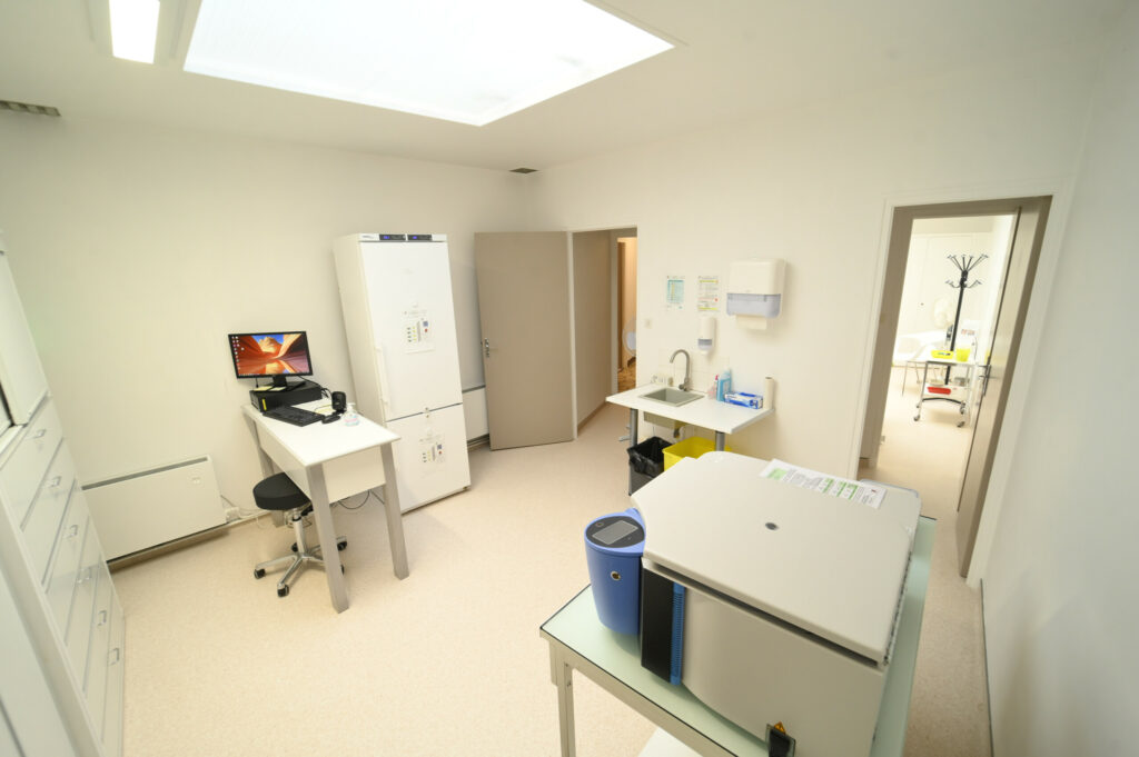 Laboratoire Vouziers Bio Ard'Aisne, lumineux et moderne avec un bureau, un ordinateur, divers équipements, un réfrigérateur et un évier, vu d'un coin avec une porte ouverte menant à une autre