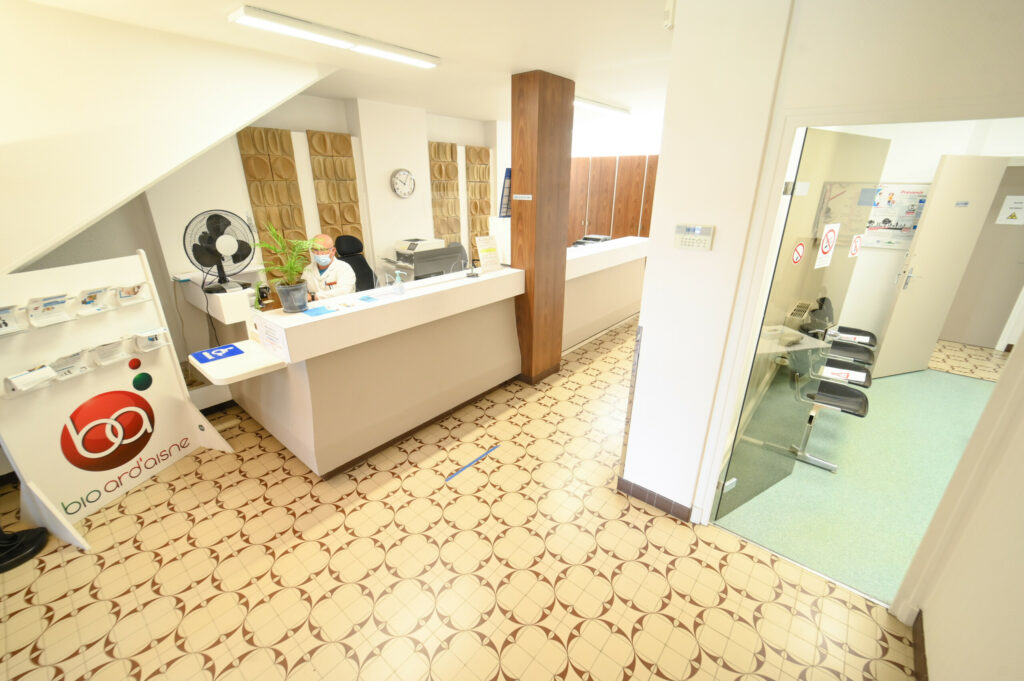 Intérieur du Laboratoire Vouziers Bio Ard'Aisne. Accueil moderne avec réception, espace d'attente et entrée des salles de soins.