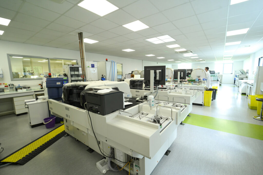 Intérieur moderne du Laboratoire Rethel Bio Ard'Aisne avec divers équipements de haute technologie et un scientifique travaillant en arrière-plan.